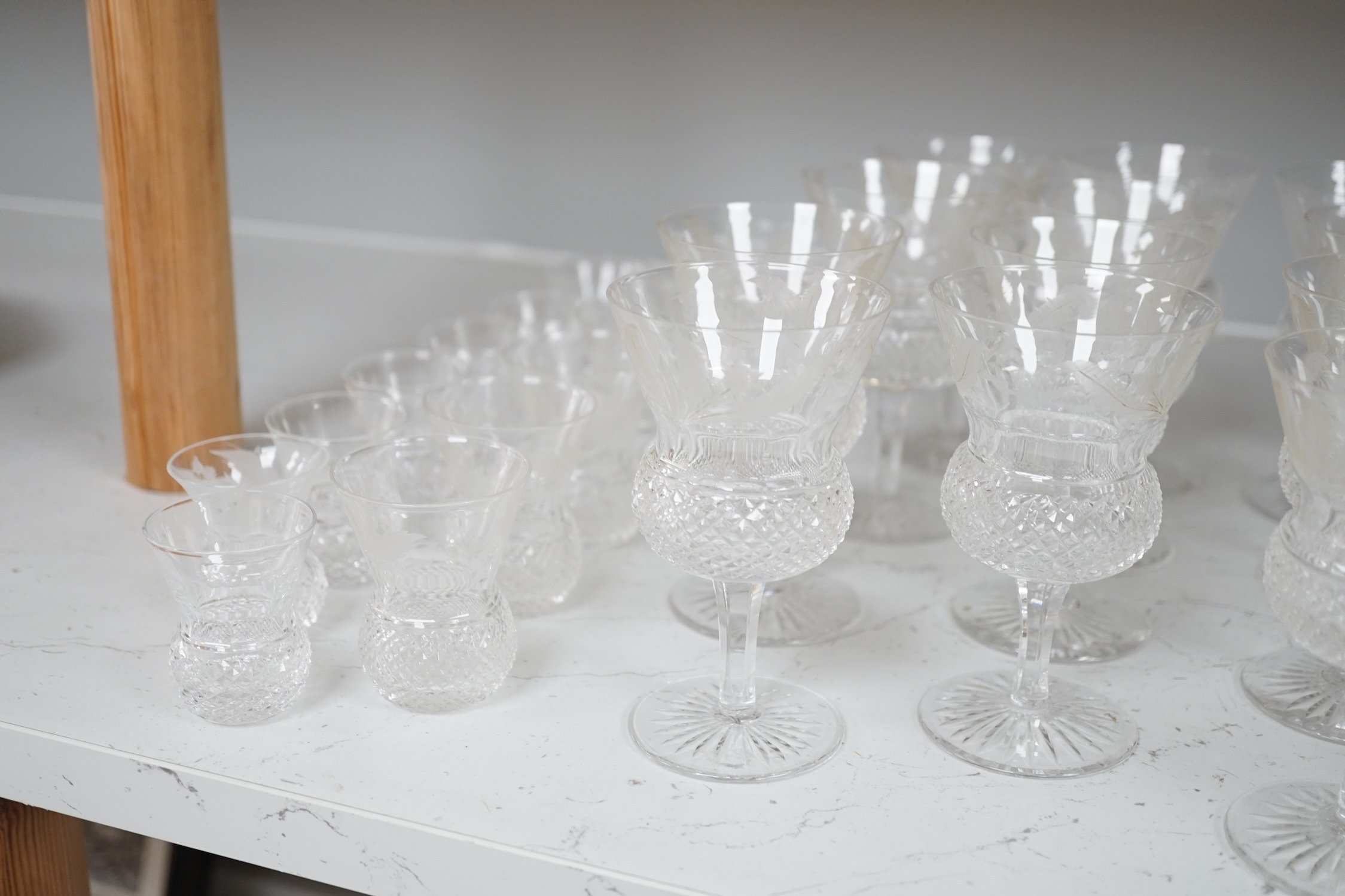 A set of twenty four Edinburgh cut glass thistle glasses and thirteen assorted smaller examples, largest 12cm high. Condition - mostly good